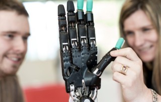 A woman and man testing out a robotic hand