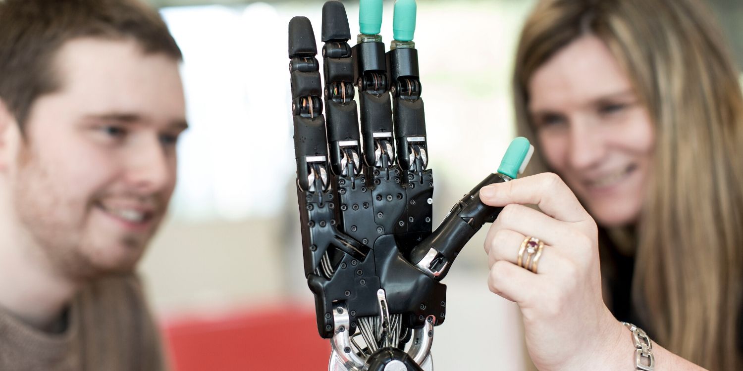 A woman and man testing out a robotic hand