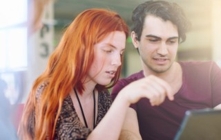 A man and woman looking at a tablet omputer.